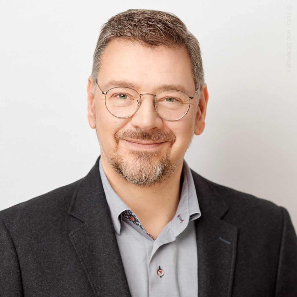 Mann lächelt freundlich Porträt in formeller Kleidung vor neutralem Hintergrund