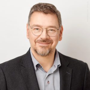 Mann lächelt freundlich Porträt in formeller Kleidung vor neutralem Hintergrund