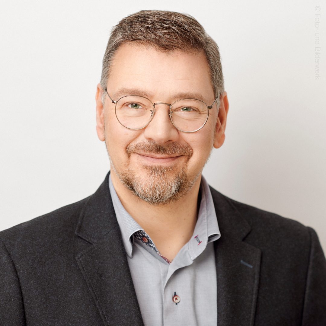 Mann lächelt freundlich Porträt in formeller Kleidung vor neutralem Hintergrund